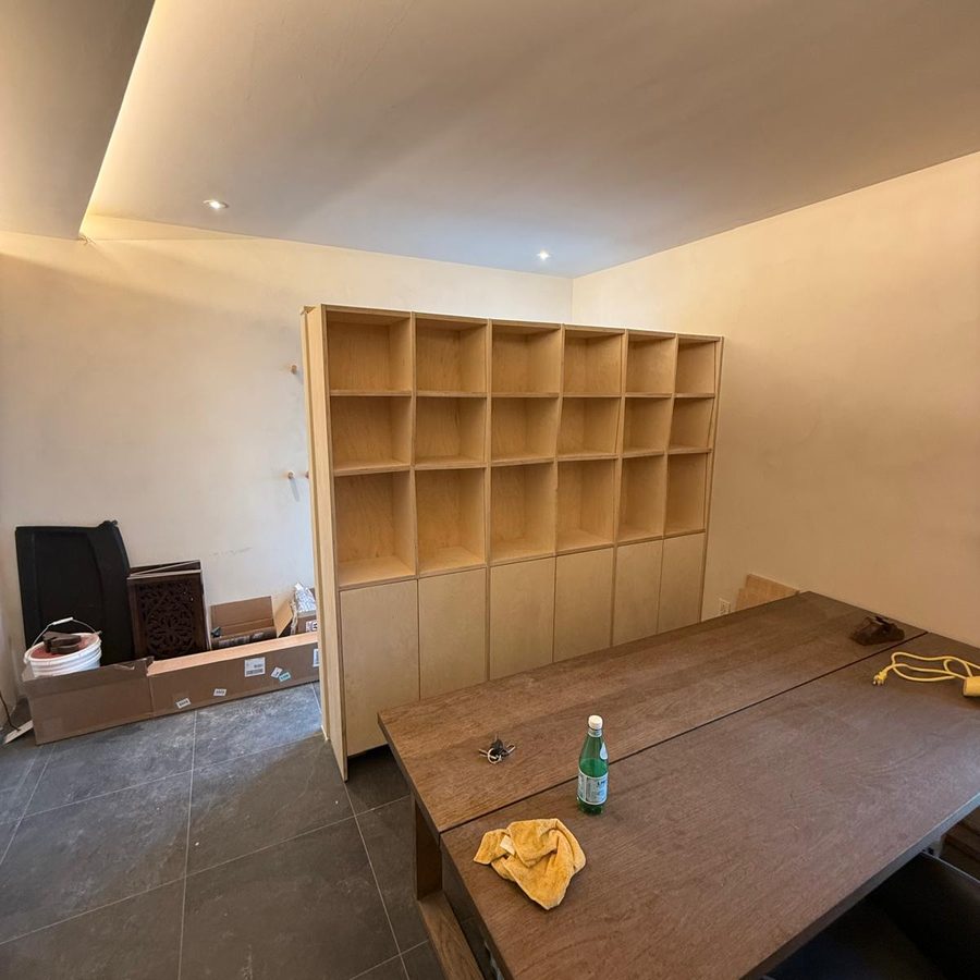 Birch bookcase installed under a cove-lit ceiling in a home office