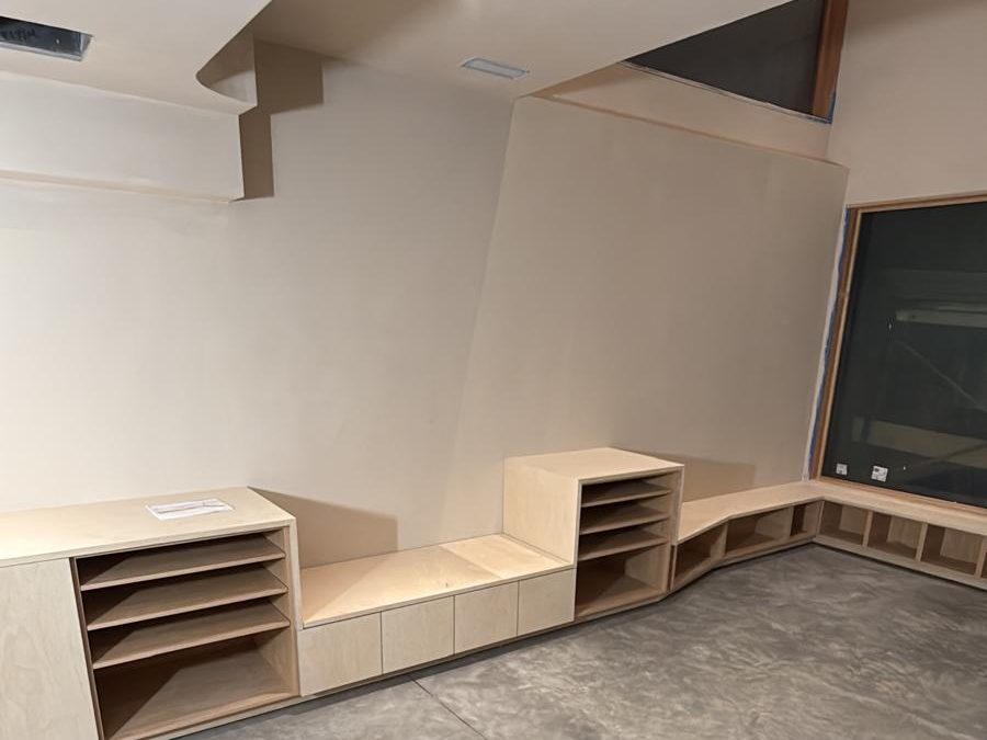 Built-in storage, bench and shelving along a freshly painted basement wall