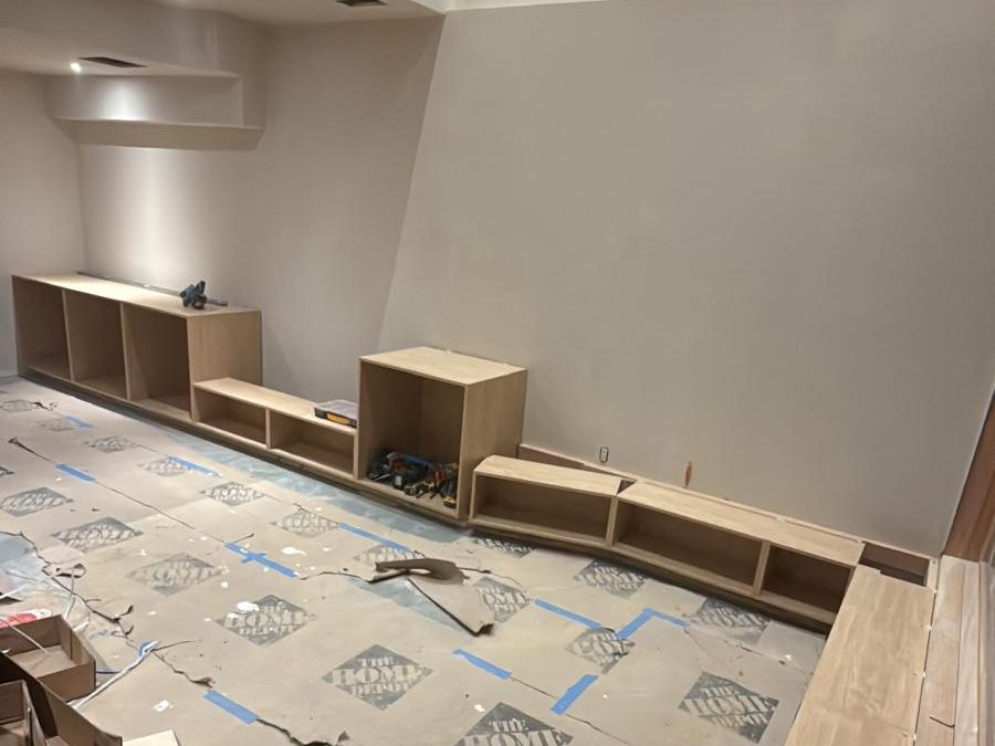 Cabinet boxes set in place along the basement wall before tops and doors