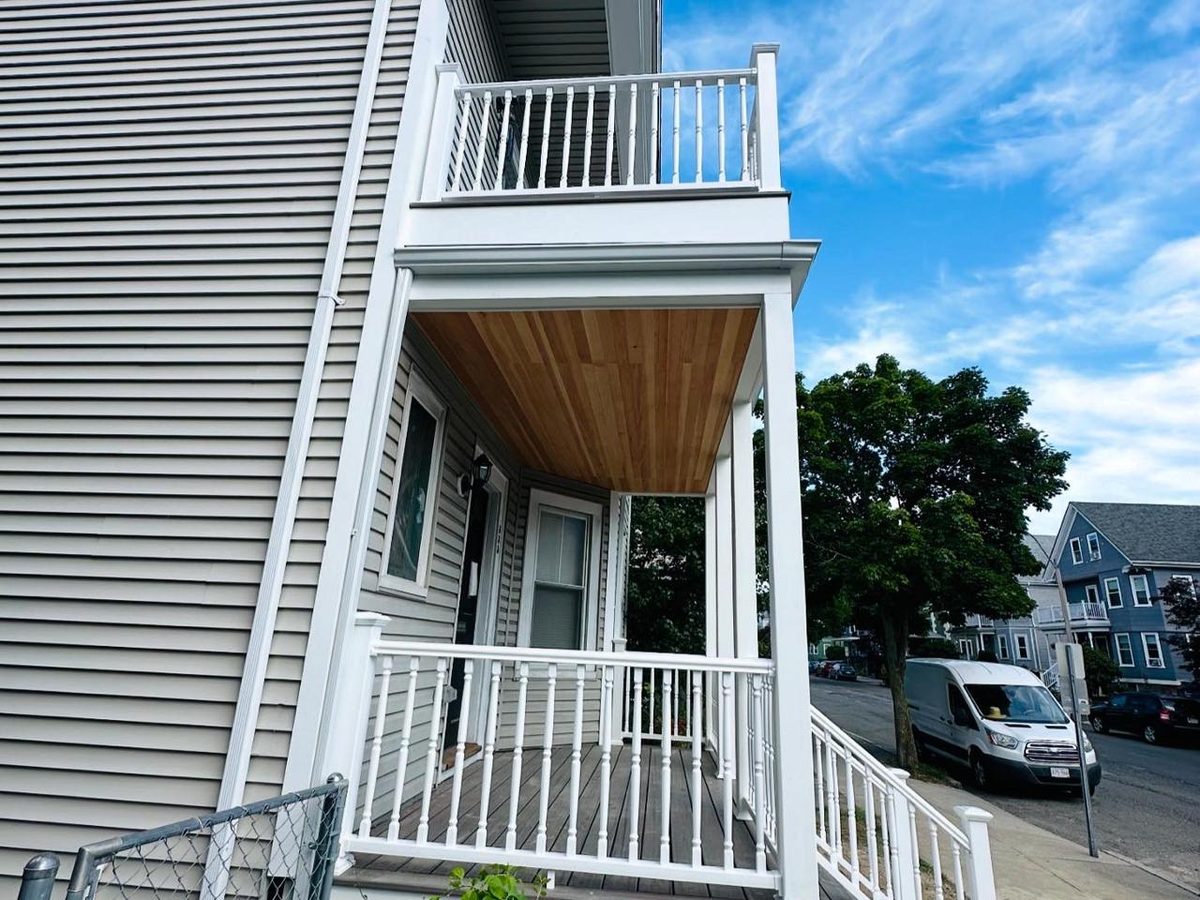 Two-story porch with composite decking, white railings, a tongue-and-groove ceiling and vinyl siding