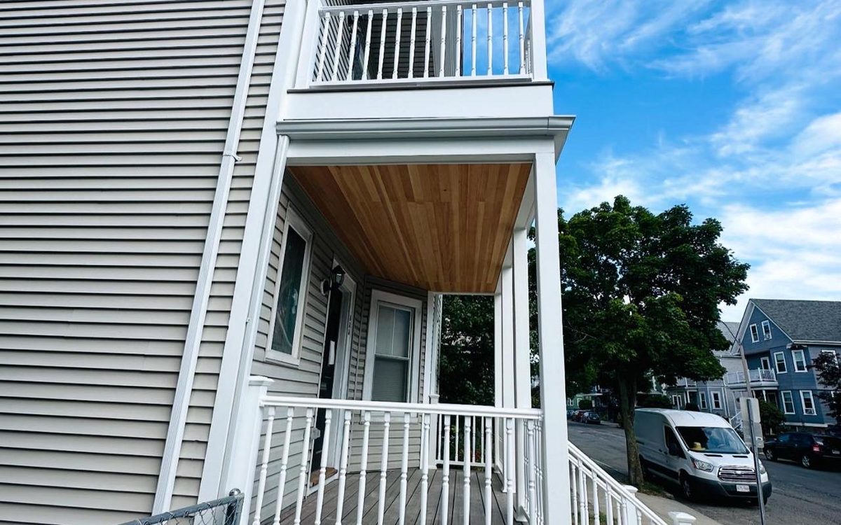 Two-story porch with composite decking, white railings, a tongue-and-groove ceiling and vinyl siding