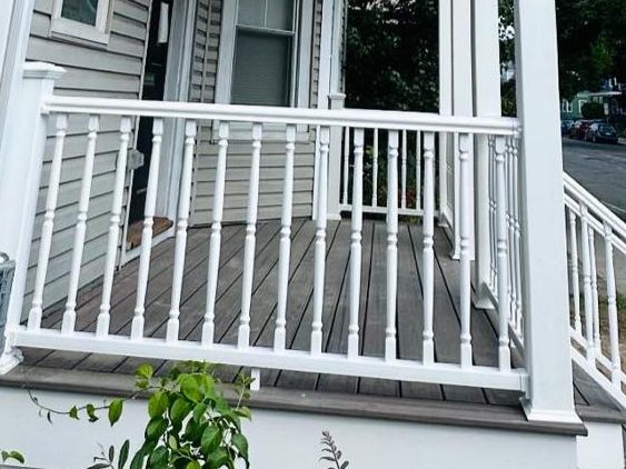 Composite porch decking framed by white turned balusters
