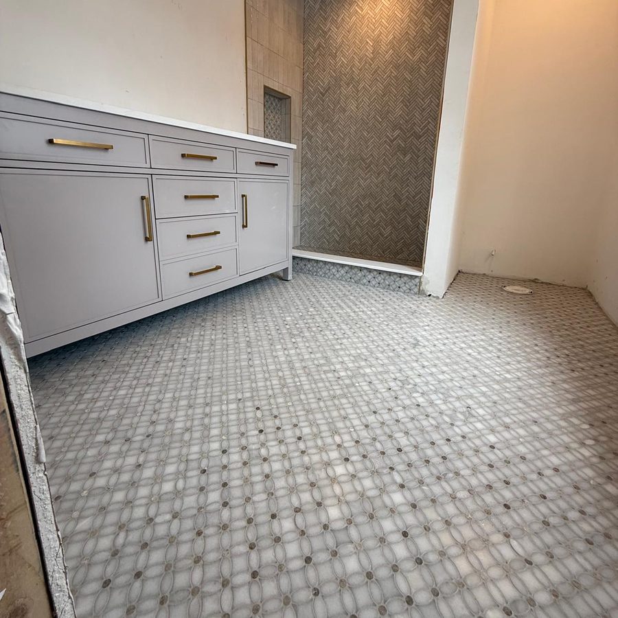 Marble flower-pattern mosaic floor running from the vanity to the herringbone shower