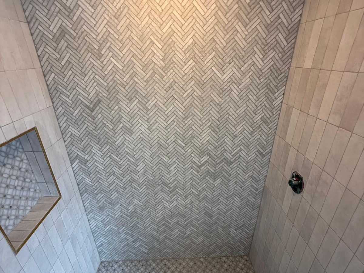 View into the herringbone shower with a centered drain and brass-trimmed niche