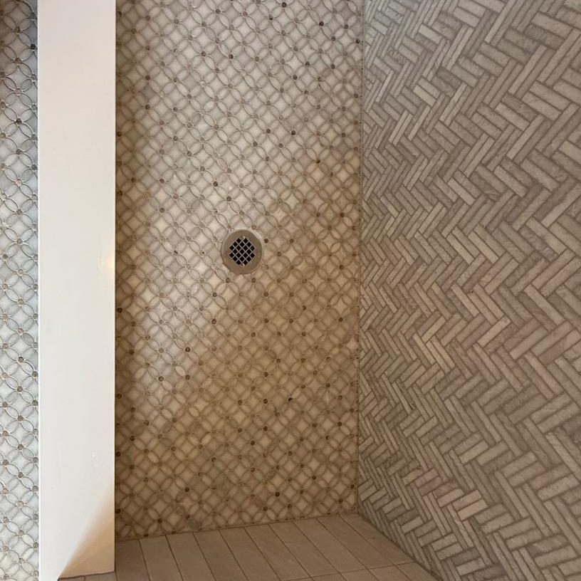 Top-down view of the shower curb between the mosaic bathroom floor and the shower floor