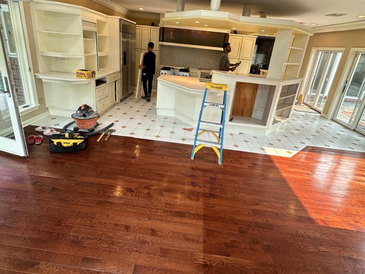 Before: Kitchen before the remodel: white cabinets, white tile with brown accents and a cherry hardwood floor