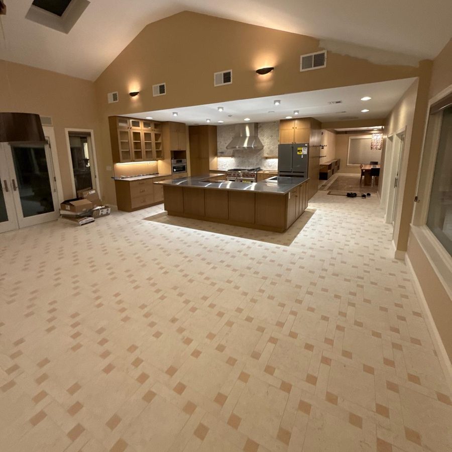 Finished kitchen and family room with woven tile floor, wood cabinets and a stainless-topped island
