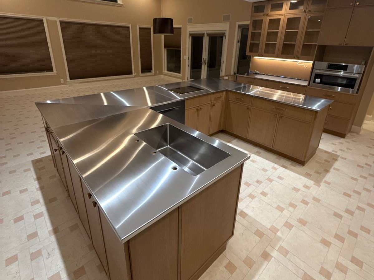 L-shaped island with a stainless steel countertop and integrated sink on the new tile floor
