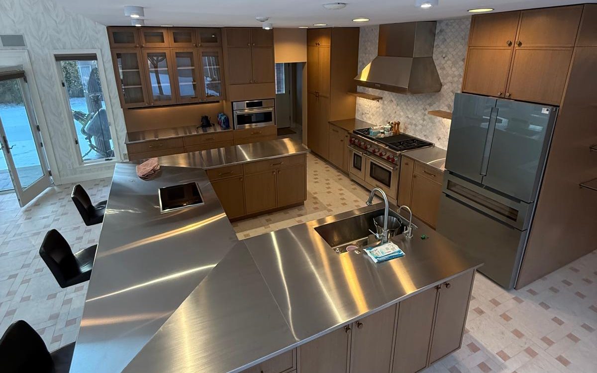 Remodeled kitchen from above: stainless island, oak cabinets, marble backsplash and woven tile floor