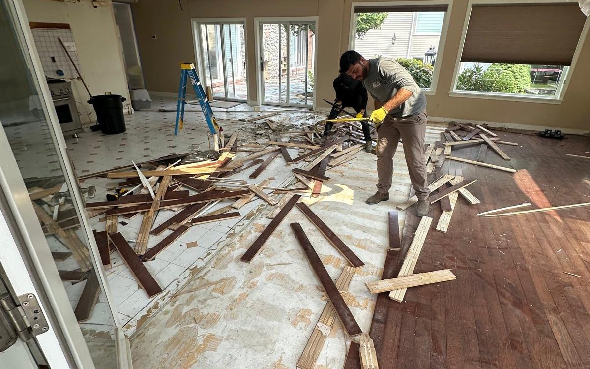 Crew tearing out the old hardwood floor during demolition