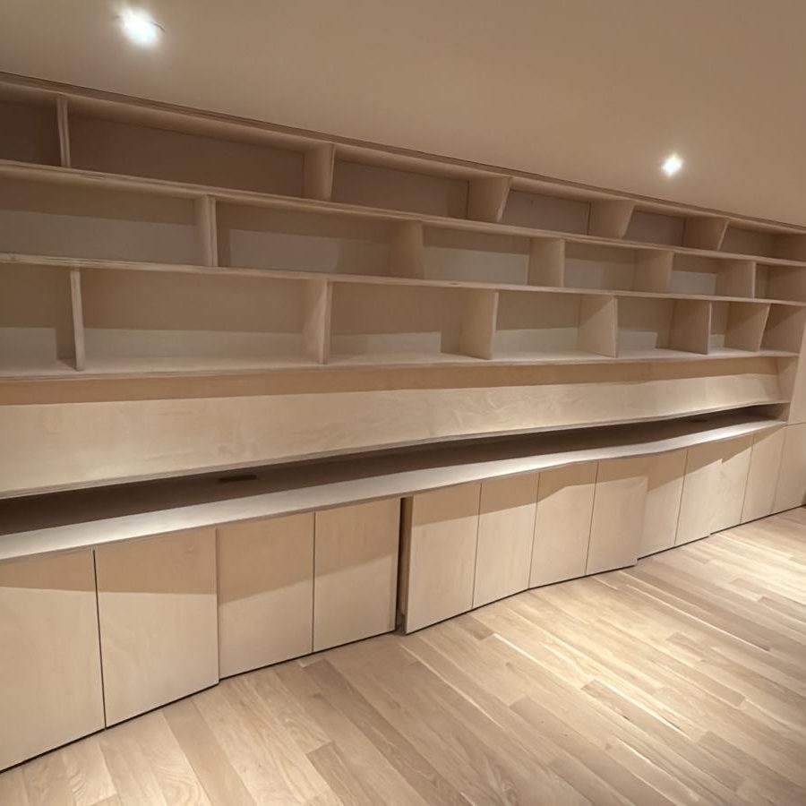 Built-in birch library wall with angled shelf dividers and recessed lighting
