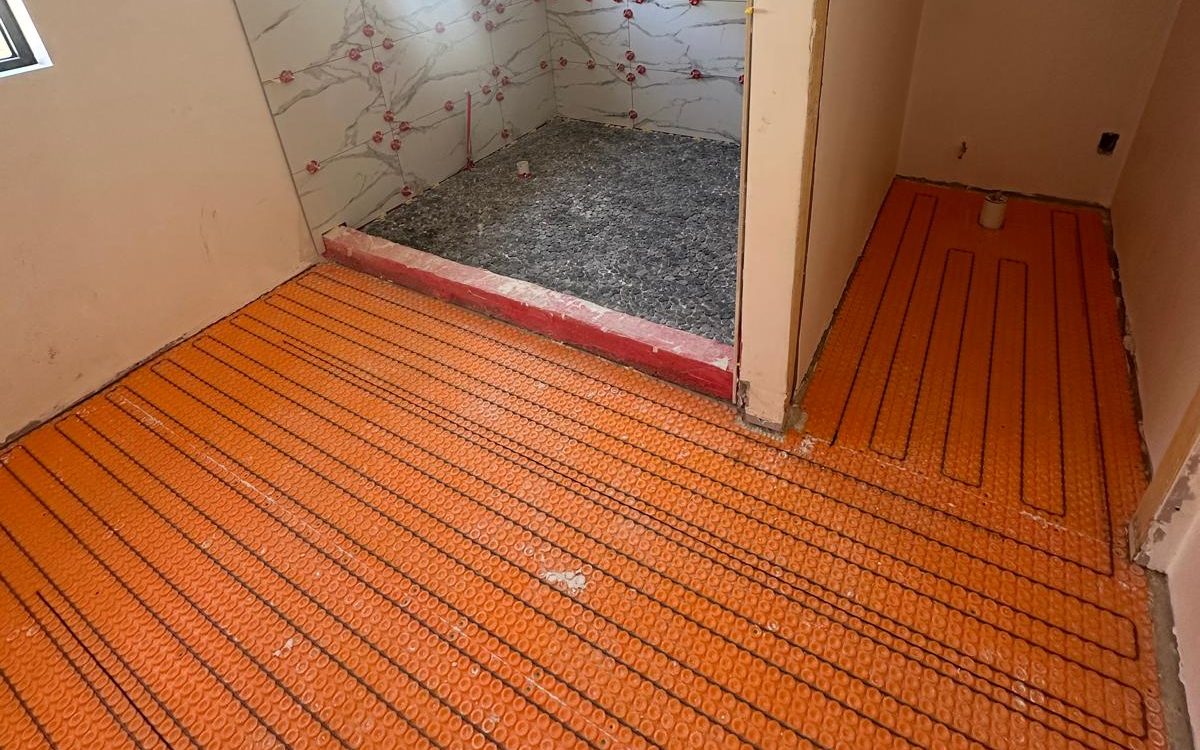 Bathroom floor covered with orange uncoupling membrane before large-format porcelain is set