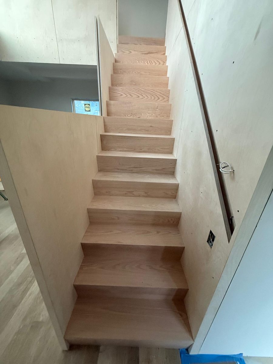 Finished stair with solid oak treads and risers between birch plywood walls