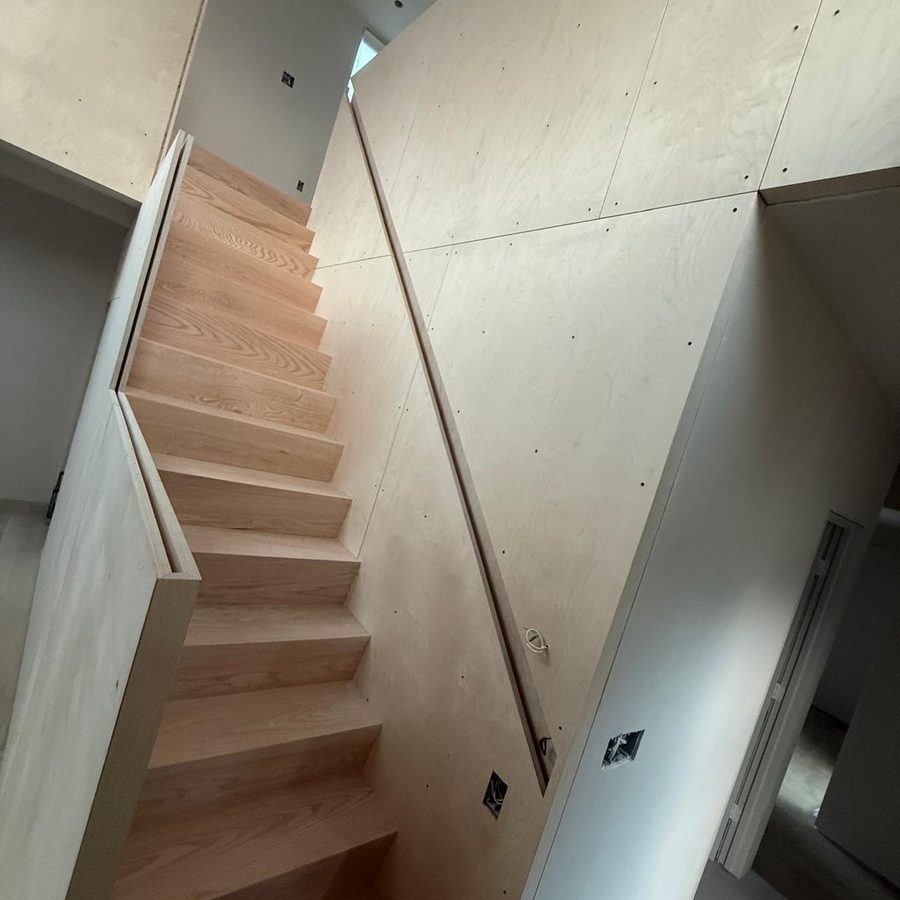 Oak stair with a recessed handrail groove cut into the birch plywood wall