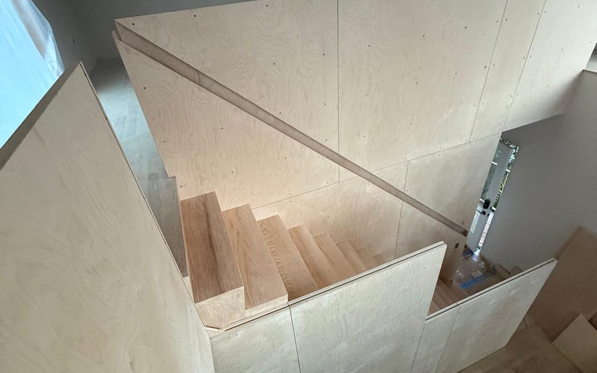 Finished oak stair turning under a skylight, seen from above