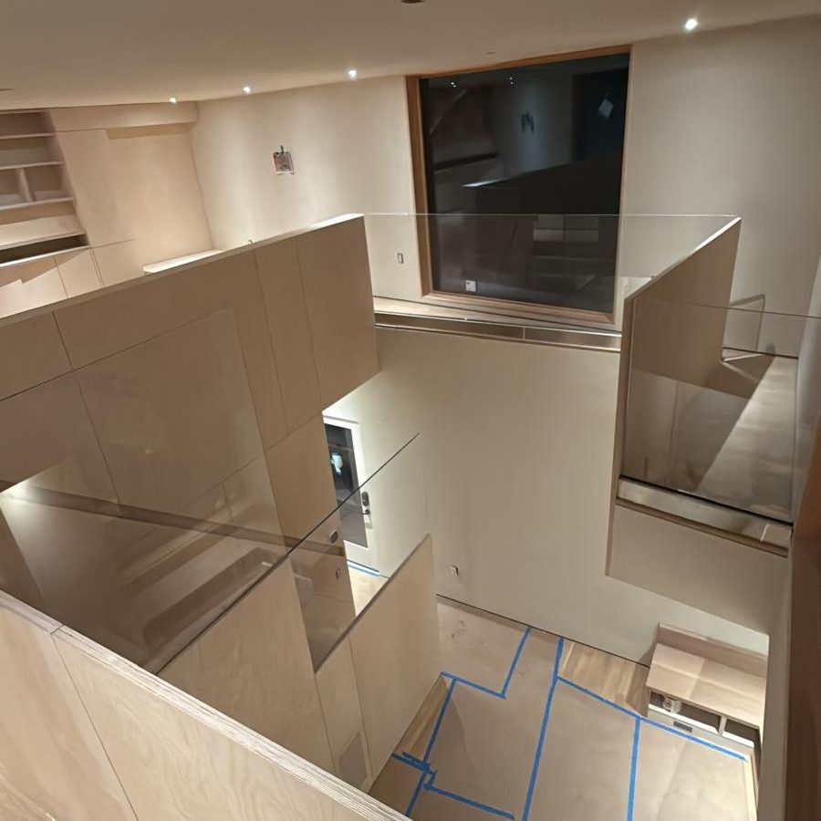 Open stairwell with glass railings and birch plywood volumes