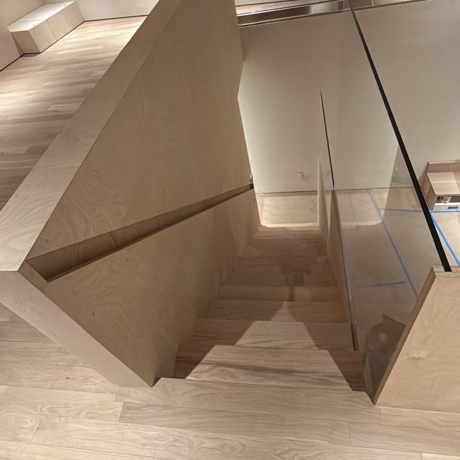 Oak stair descending beside a frameless glass railing