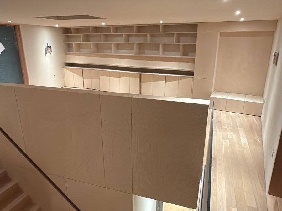 Built-in shelving wall and the oak stair seen from the upper landing