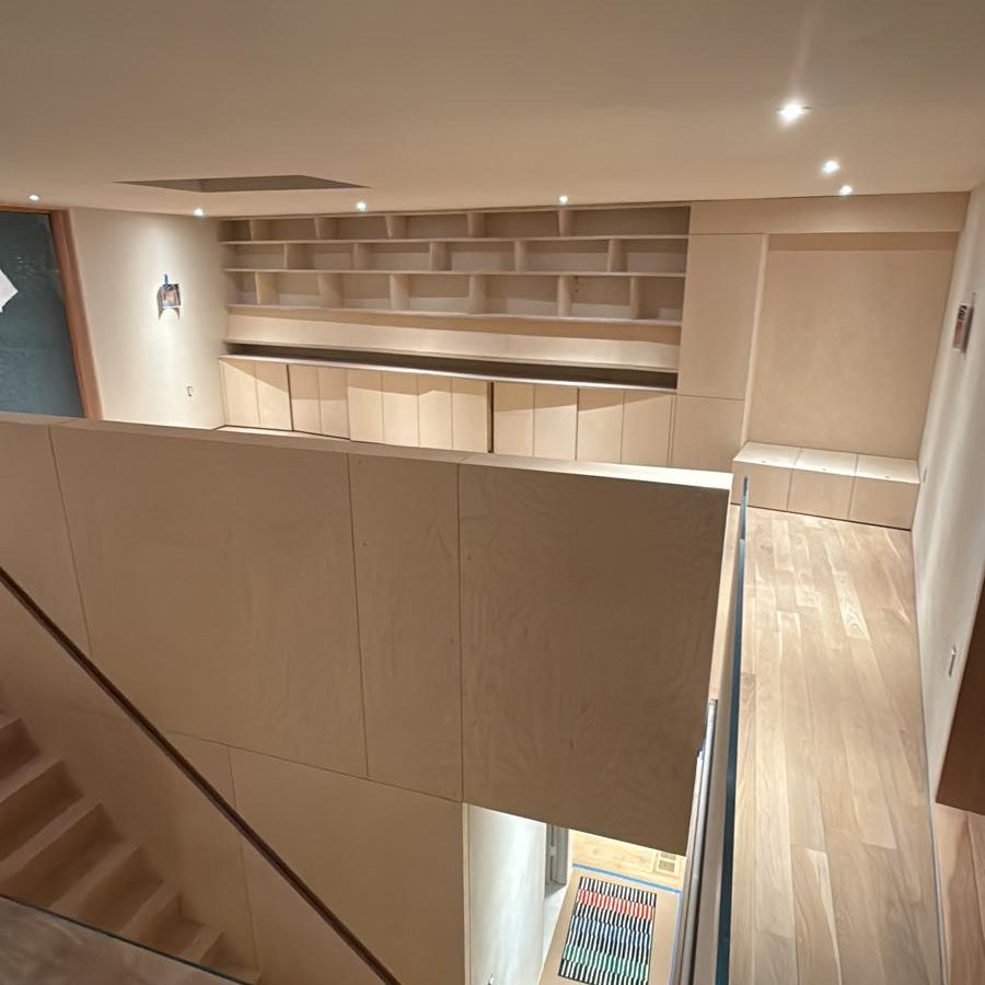 Built-in shelving wall and the oak stair seen from the upper landing