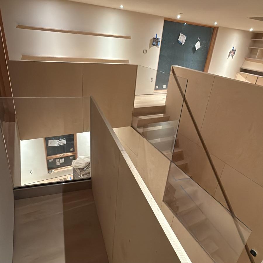 Upper-floor glass railing above the panel-wrapped stair