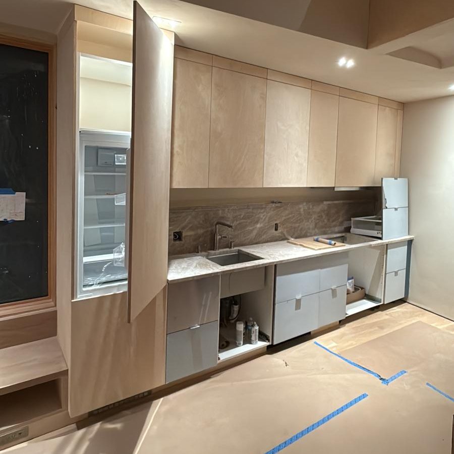 Birch plywood kitchen with an integrated refrigerator panel and stone backsplash