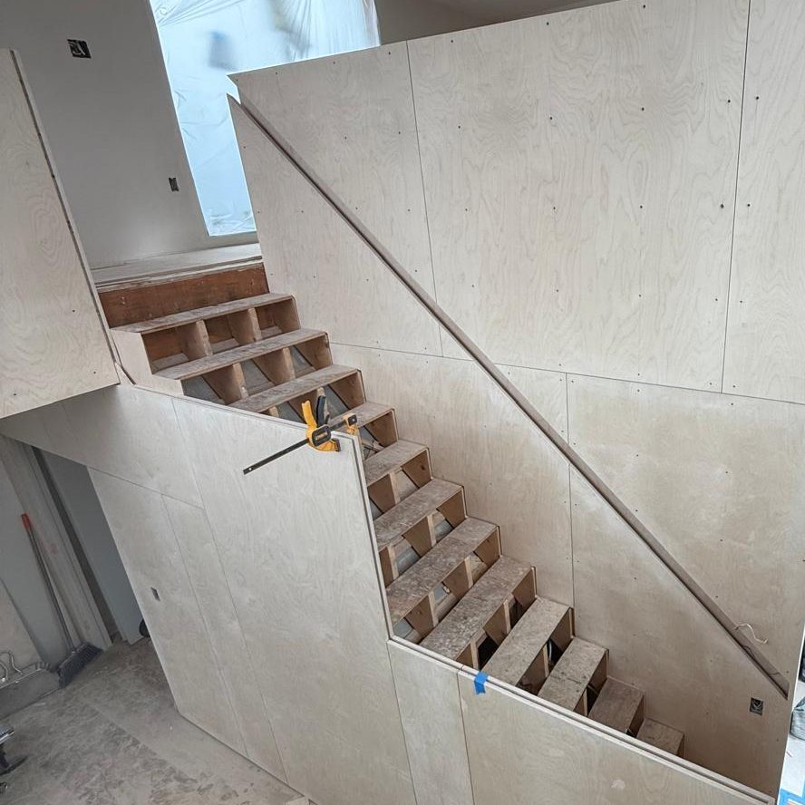 Birch plywood panels wrapping the stair, seen from the upper landing