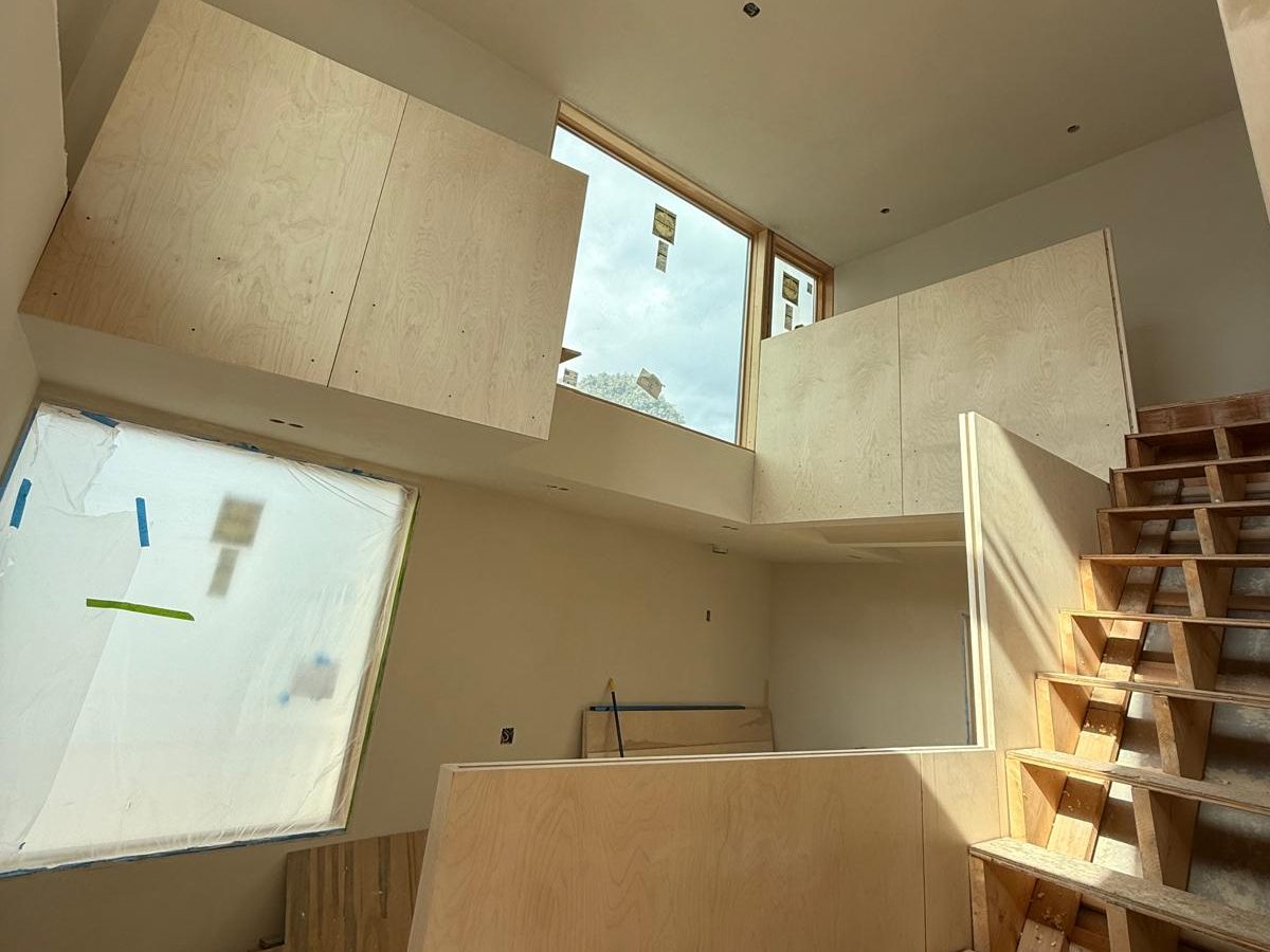 Birch plywood landing walls under tall windows in a double-height hall