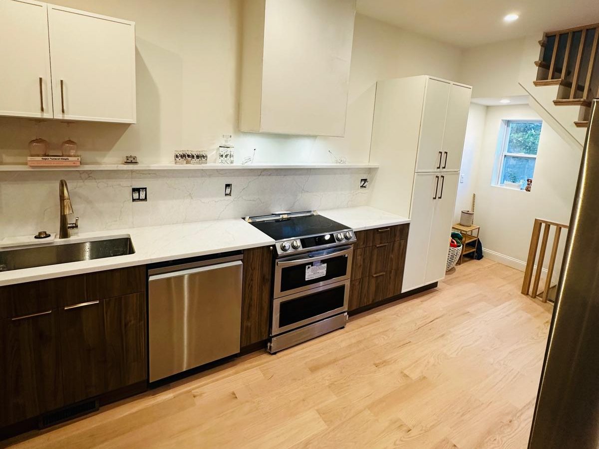Kitchen wall with walnut base cabinets, quartz backsplash and a floating shelf
