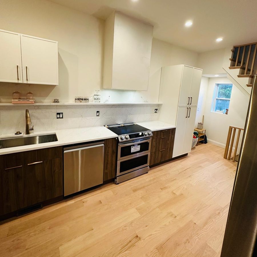Kitchen wall with walnut base cabinets, quartz backsplash and a floating shelf