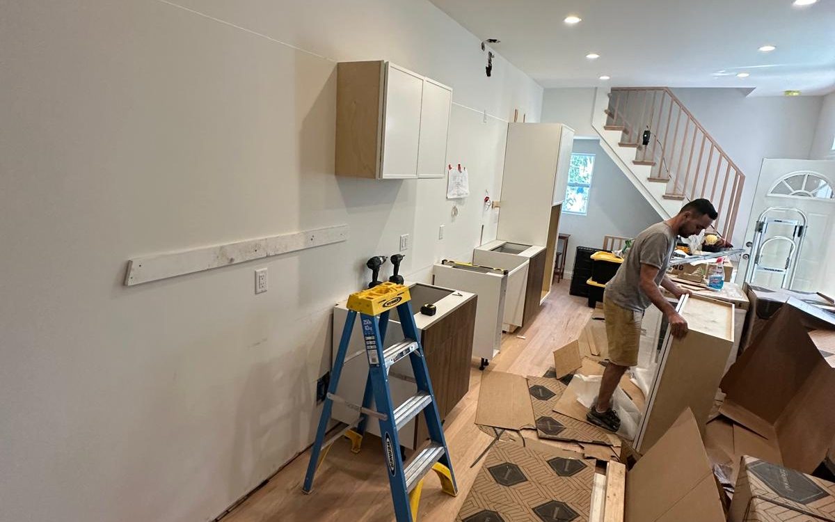 Crew installing kitchen cabinets on the new oak floor