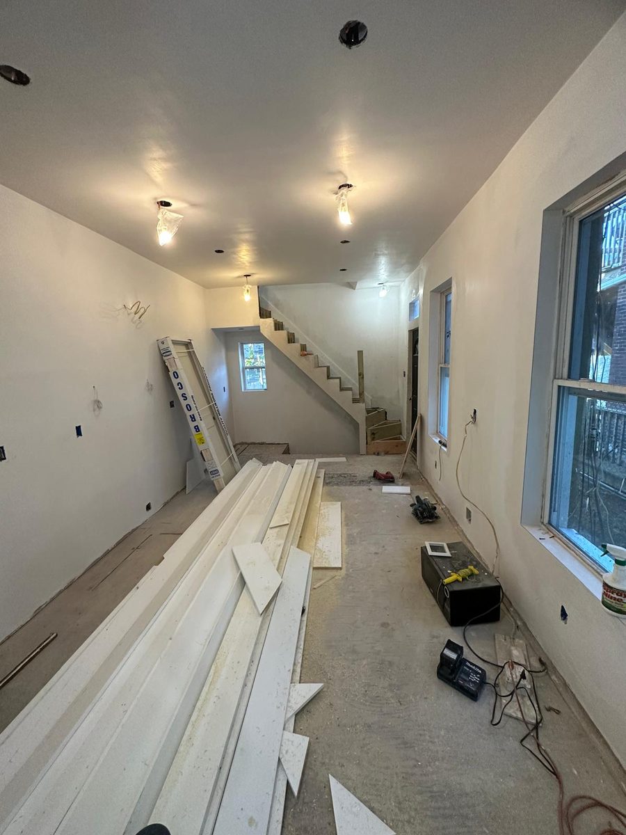 Trim boards laid out in a freshly painted room as the new stair goes in
