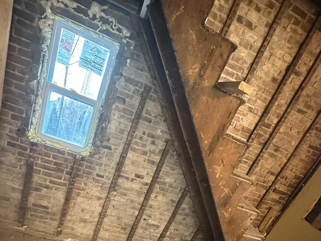 Old stair against the exposed brick wall, with a new window foam-sealed in place