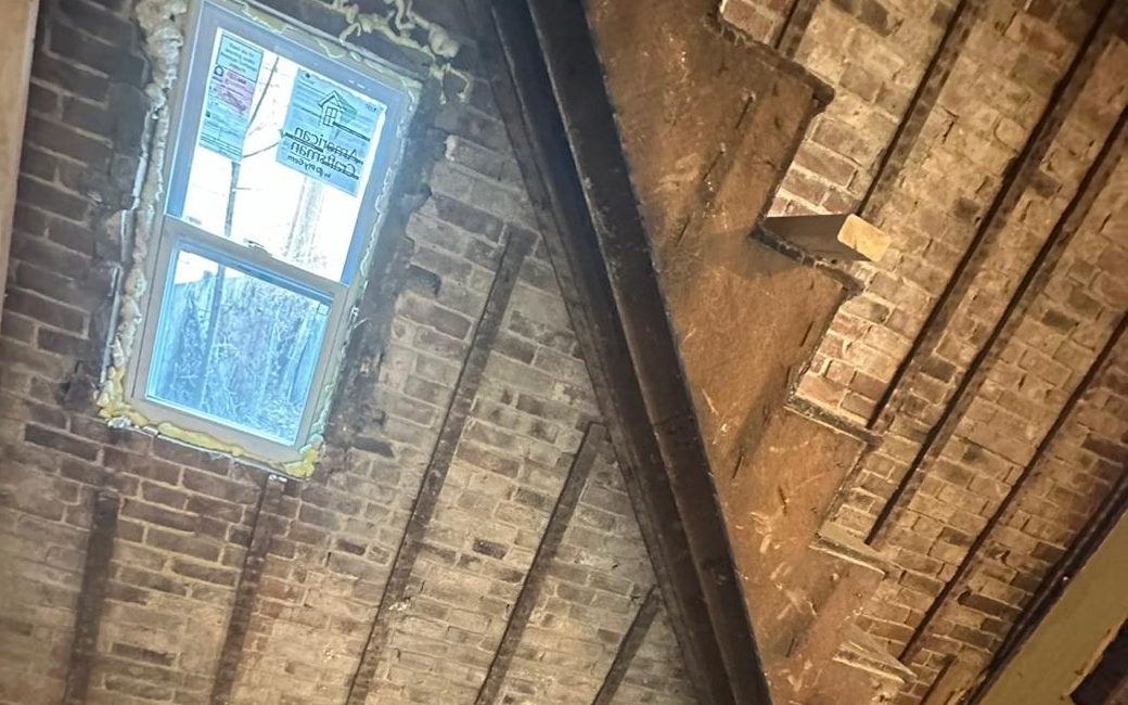 Old stair against the exposed brick wall, with a new window foam-sealed in place